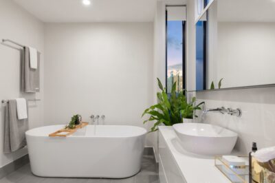 A modern bathroom with a generously sized bathtub and a large window, providing an abundance of natural light