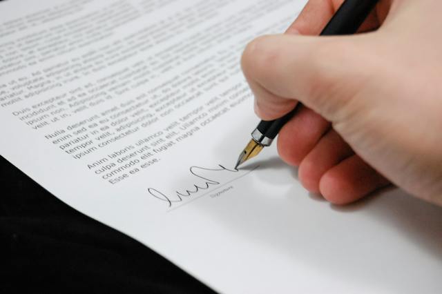 An individual signing a contract with a pen, demonstrating commitment and legal agreement