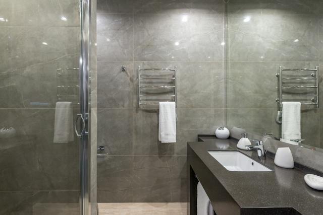 A modern bathroom featuring a marble vanity counter, a sleek sink, and a spacious shower
