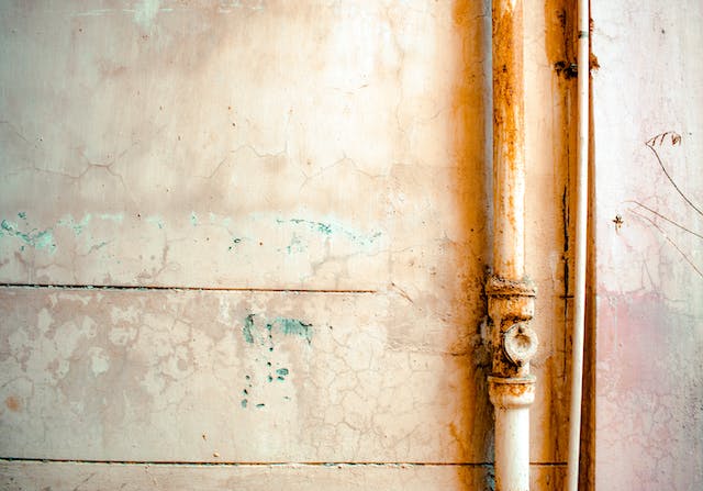 Rusty white pipe against white wall