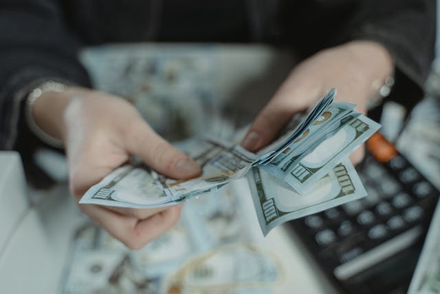 A person counting money in front of a calculator