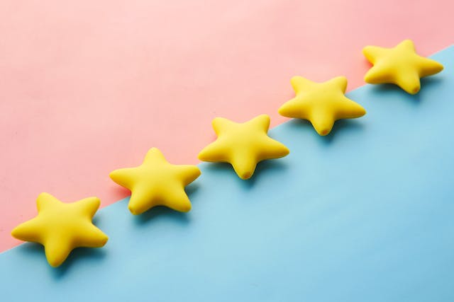 Five yellow star-shaped toys arranged on a vibrant blue and pink background
