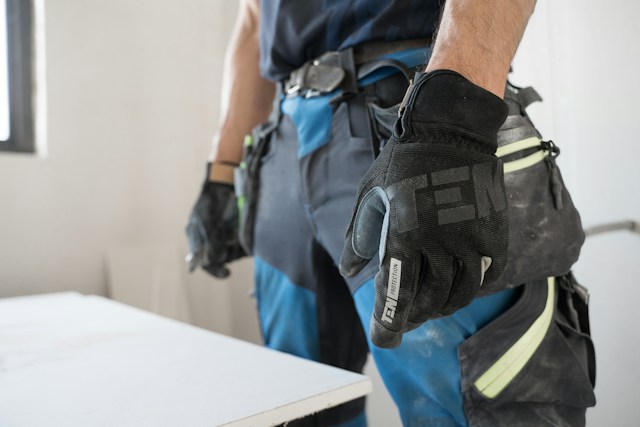 A worker with gloves and a refinishing tool in hand
