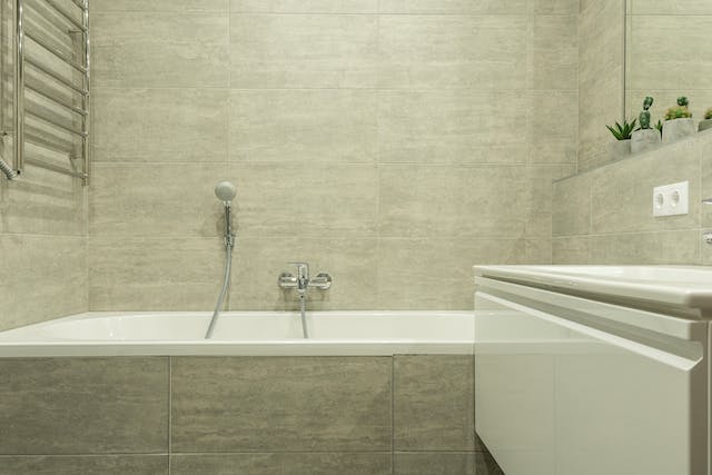 A refinished bathroom featuring a sleek sink, a luxurious bathtub, and an elegant mirror
