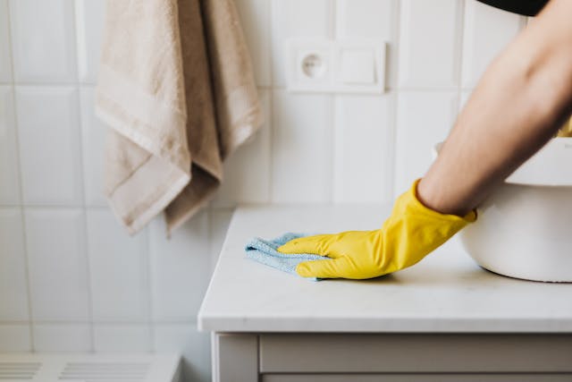 A person in yellow gloves meticulously cleaning a countertop with a cloth