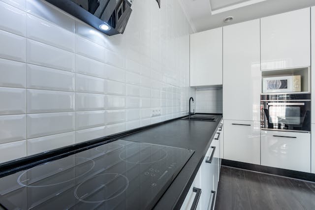 A kitchen featuring white cabinets and black countertops, creating a sleek and modern aesthetic