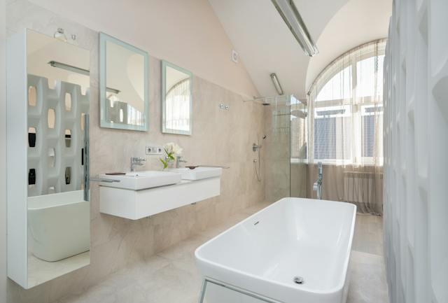 A formal bathroom showcasing a pristine white bathtub and a sleek sink with elegant fixtures