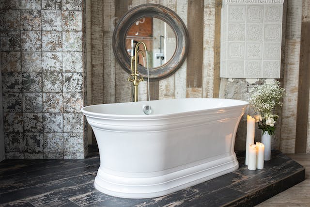 A pristine white bathtub placed in a well-lit room, accompanied by a sleek mirror on the wall.