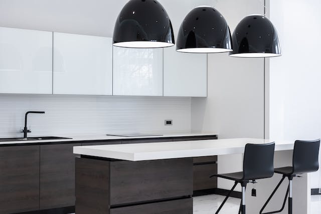 A contemporary kitchen adorned with black and white pendant lights, casting a stylish glow over the countertop