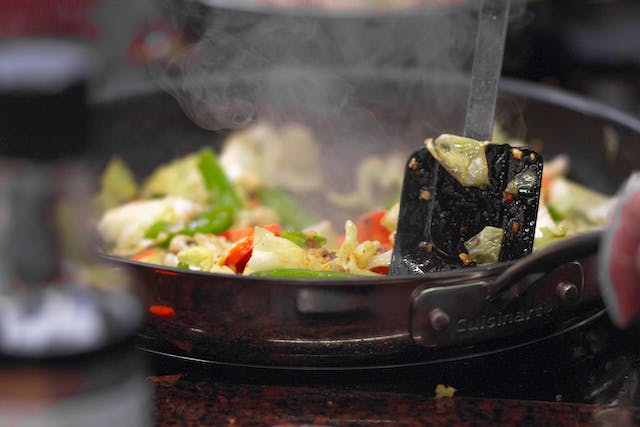 A steaming pan of food being cooked on a hot stove