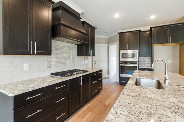 A kitchen featuring sleek dark cabinets and polished granite counter tops