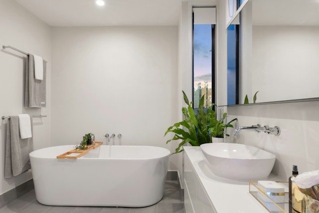 A modern bathroom with a generously sized bathtub and a large window, providing an abundance of natural light.