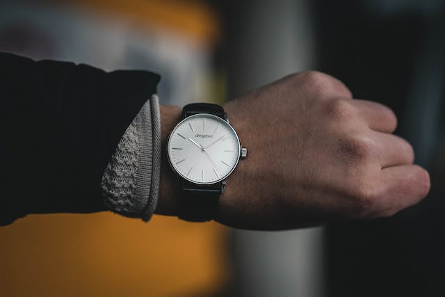 A person adorning a sophisticated white watch, complementing their outfit with a touch of refinement