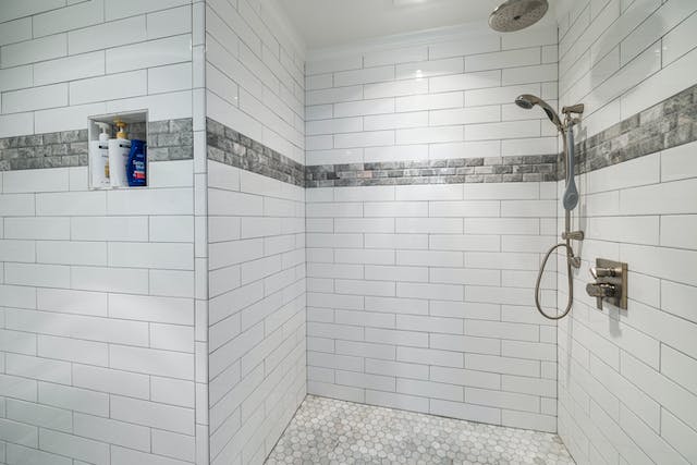 An elegant shower area showcasing pristine white tiles and a sleek shower head