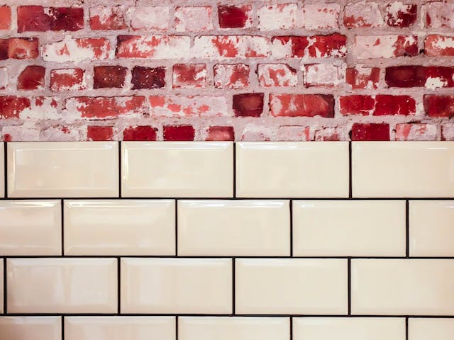 A backdrop of a red brick wall with neatly arranged white tiles