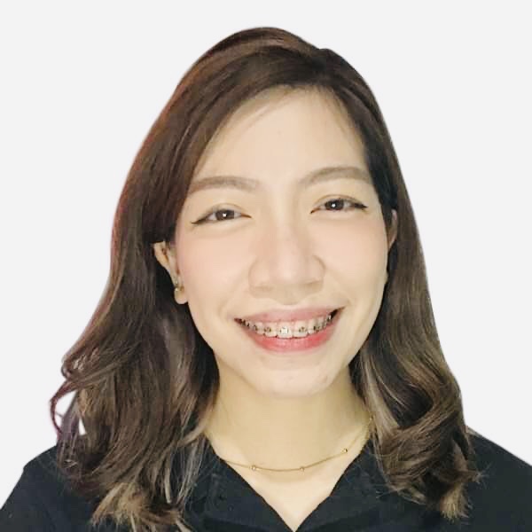 A smiling woman with shoulder-length hair and braces on their teeth against a white background.